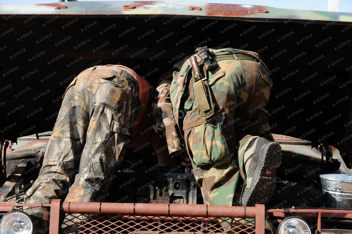 Two Men in Camo Fatigues Working Under Truck Hood, Vehicle Engine Maintenance